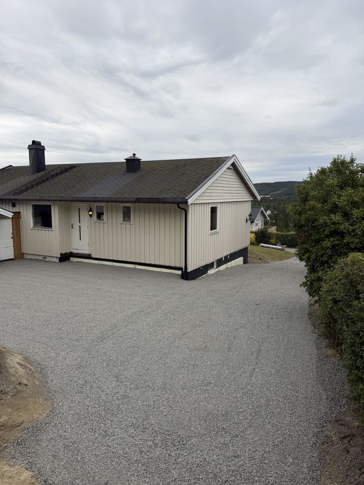 Det samme hvite huset etter drenering, med ny grusplass foran