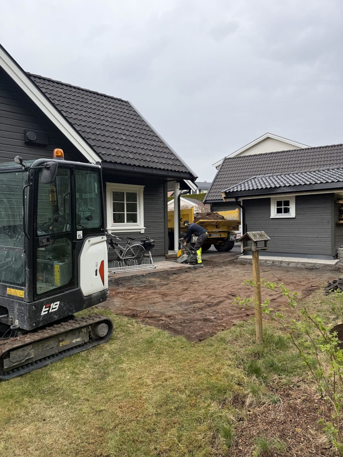 Minigraver i hagen foran et grått hus, der gammelt gress er fjernet