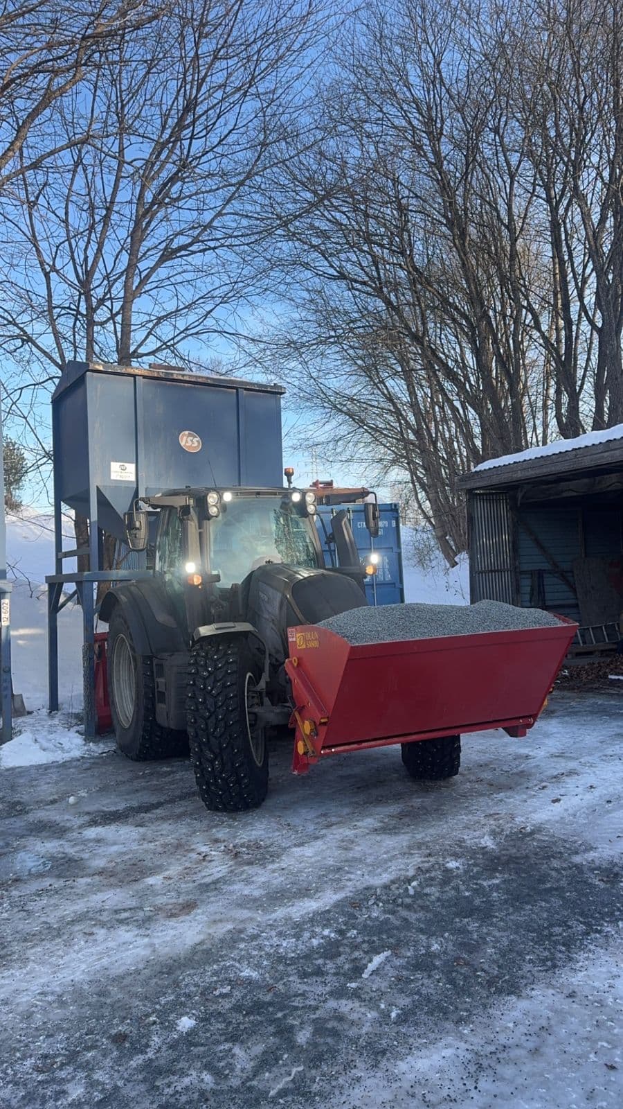 Traktor med strøkasse full av grus, klar til å strø